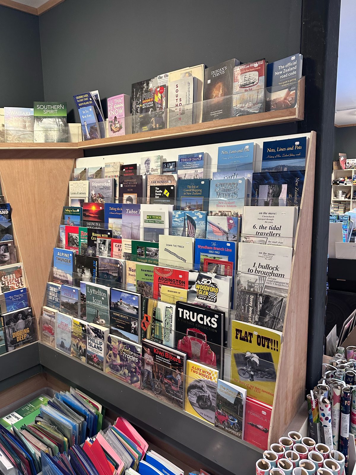 Rack of New Zealand and Lyttelton local history books at Leslie’s Bookshop, including Lyttelton Icon, Tides of Change, Nets Lines and Pots and motoring titles