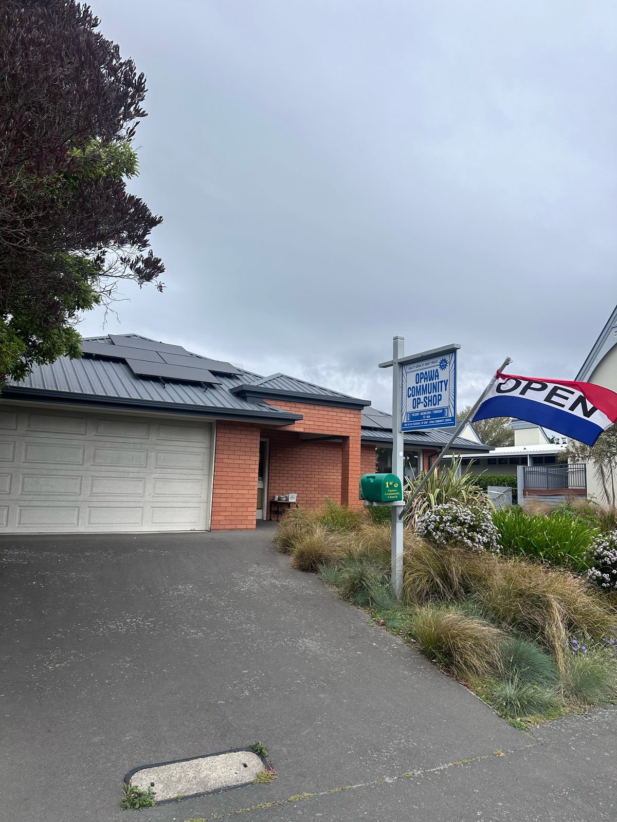 Opawa Community Op-Shop exterior at 158 Opawa Road, Christchurch, with sign and OPEN flag