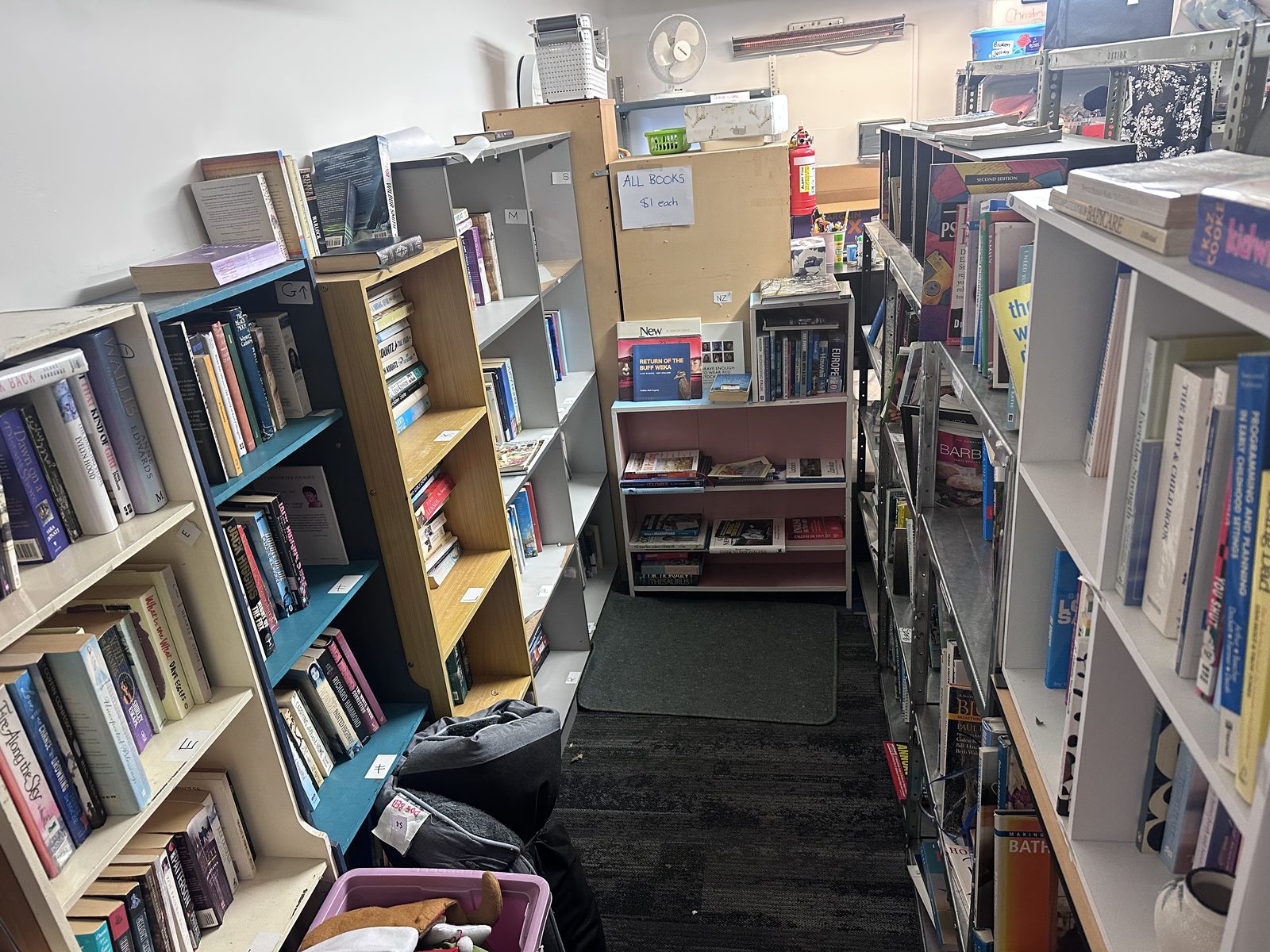 Book room at Opawa Community Op-Shop with fiction and non-fiction bookcases and an ALL BOOKS $1 each sign