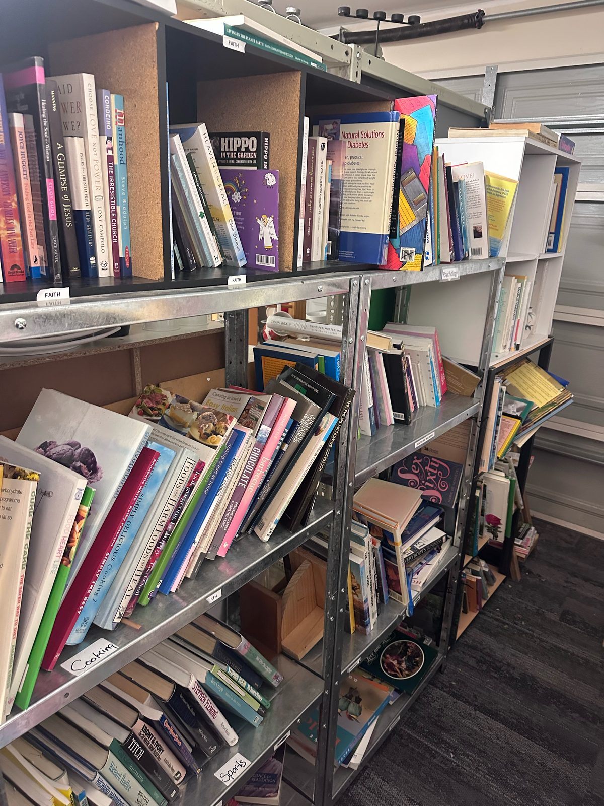 Labelled shelves of faith, cooking, sports and health books at Opawa Community Op-Shop